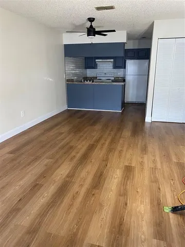 a room with kitchen island granite countertop wooden floors and a sink