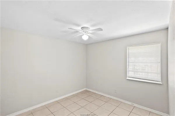 an empty room with windows and fan