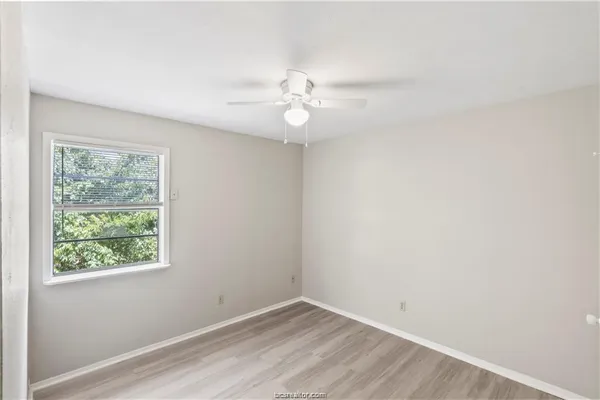 an empty room with a window and ceiling fan