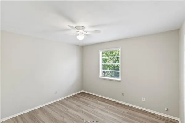 an empty room with a window and ceiling fan