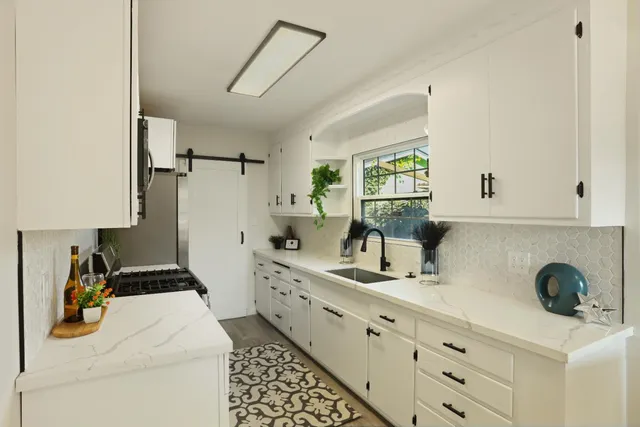 a kitchen with white cabinets and sink