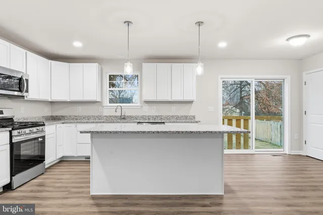 a kitchen with stainless steel appliances granite countertop a stove a sink dishwasher a refrigerator and a microwave oven with wooden floor