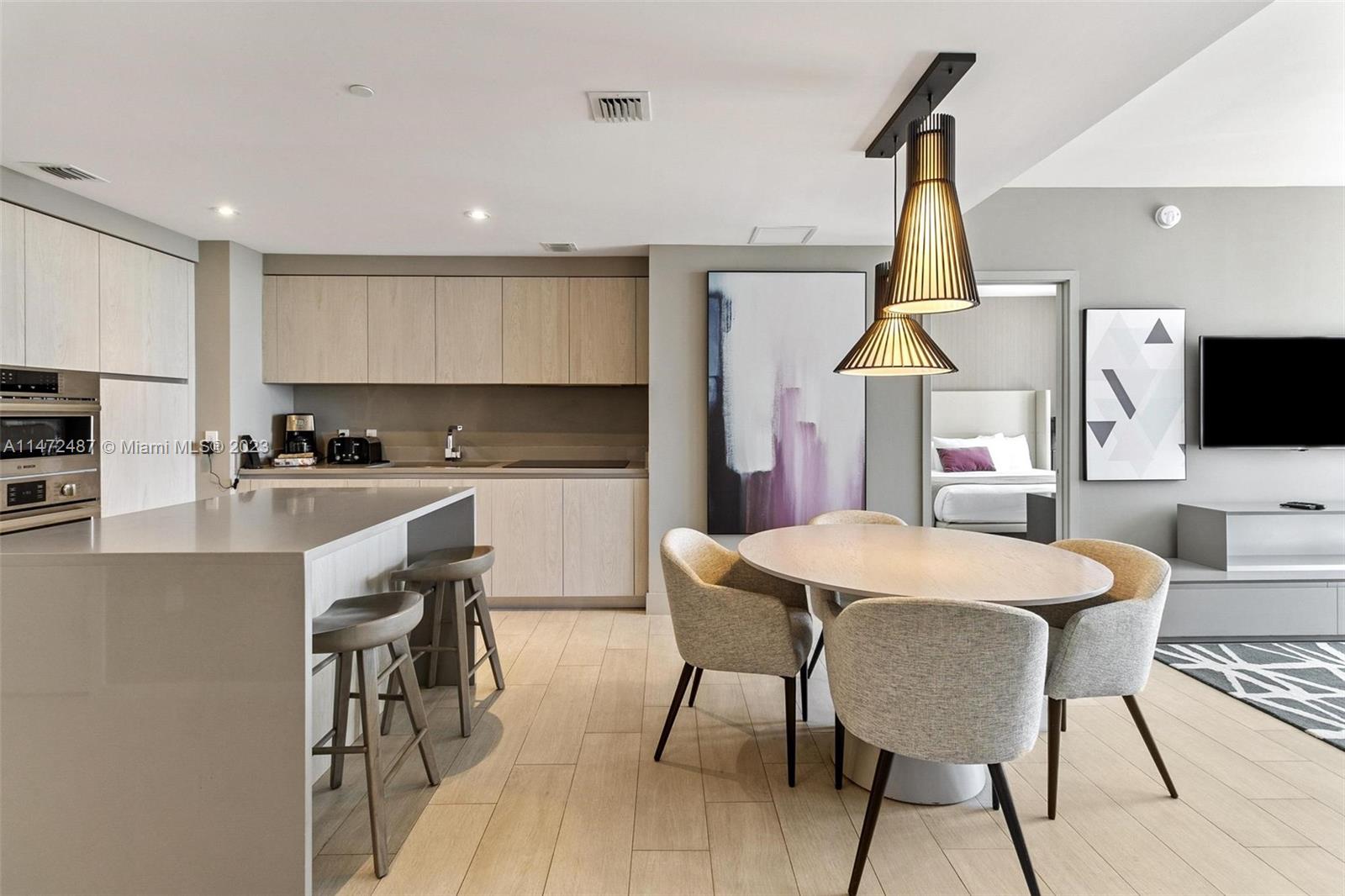 4010 South Ocean Drive, Unit R1107 Hollywood, FL 33019 - Photo 6 of 25 a kitchen with stainless steel appliances a table chairs refrigerator and microwave