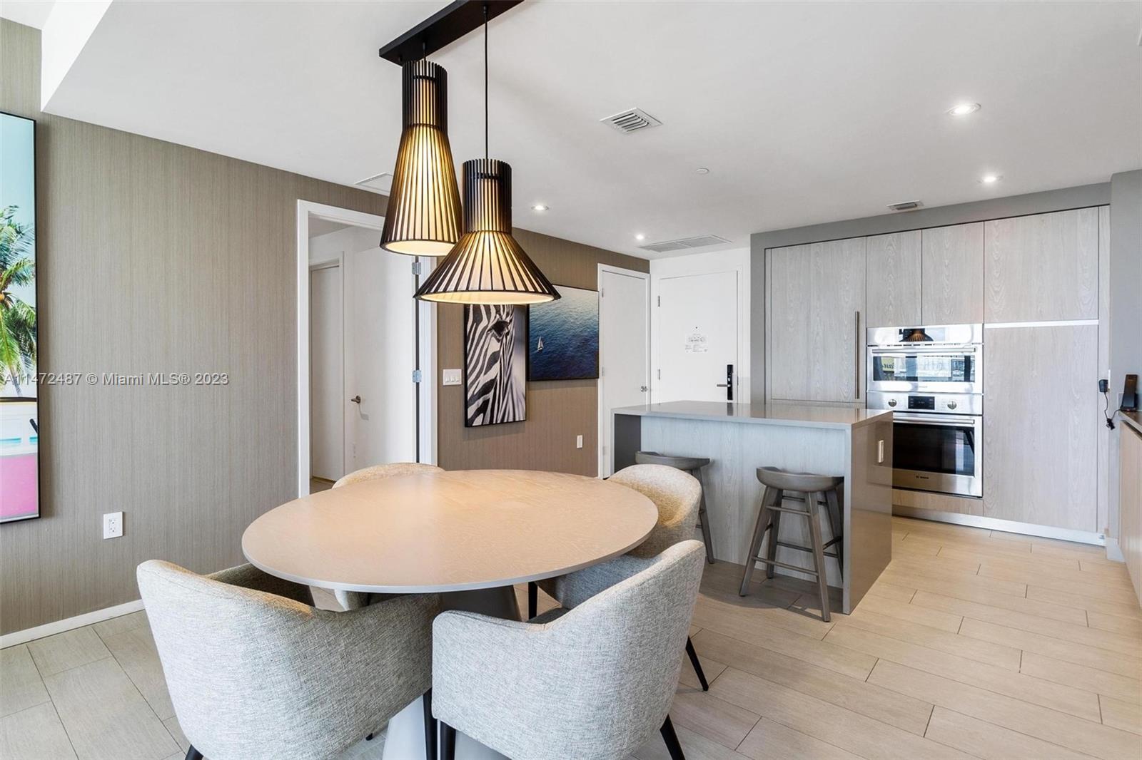 4010 South Ocean Drive, Unit R1107 Hollywood, FL 33019 - Photo 10 of 25 a kitchen with stainless steel appliances a dining table chairs and stove top oven
