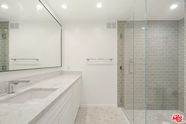 a bathroom with a granite countertop sink a mirror and shower