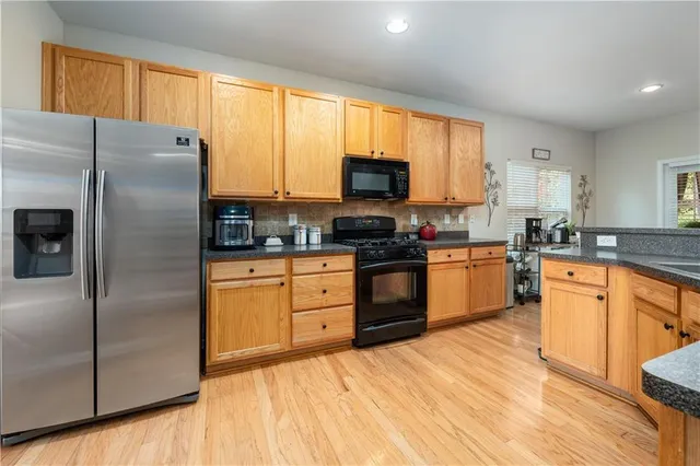 a large kitchen with stainless steel appliances granite countertop a stove a sink dishwasher and a microwave oven with cabinets