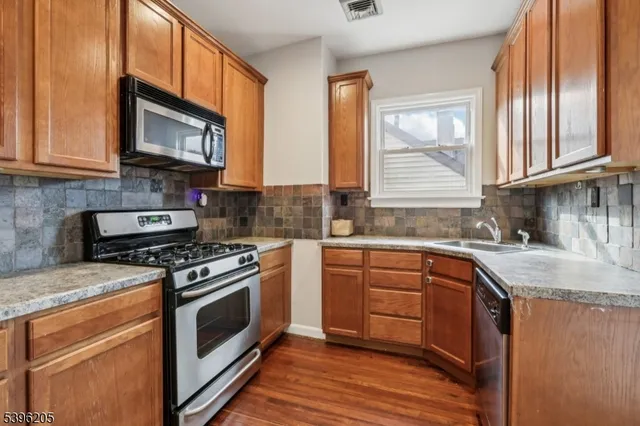 a kitchen with stainless steel appliances granite countertop a stove a sink and a microwave