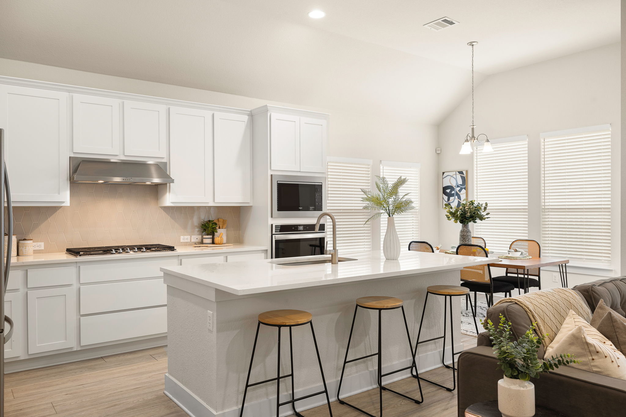 20904 Carries Ranch Road Pflugerville, TX 78660 - Photo 13 of 33 a kitchen with stainless steel appliances kitchen island granite countertop a stove a sink a microwave a dining table and chairs with white cabinets