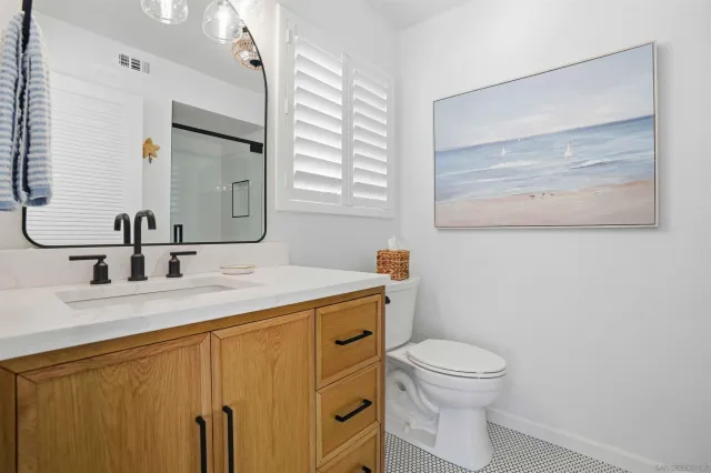 a bathroom with a granite countertop toilet sink and mirror