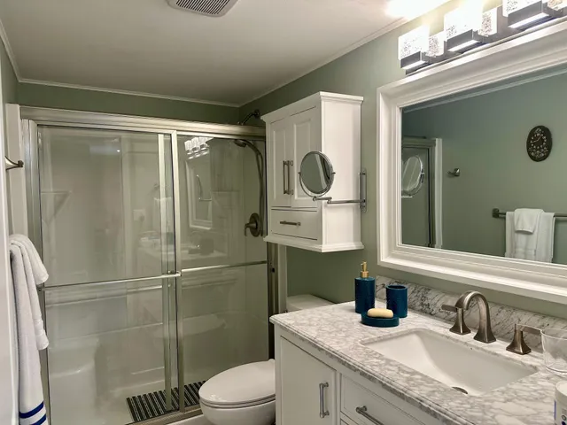 a bathroom with a granite countertop sink toilet a mirror and shower