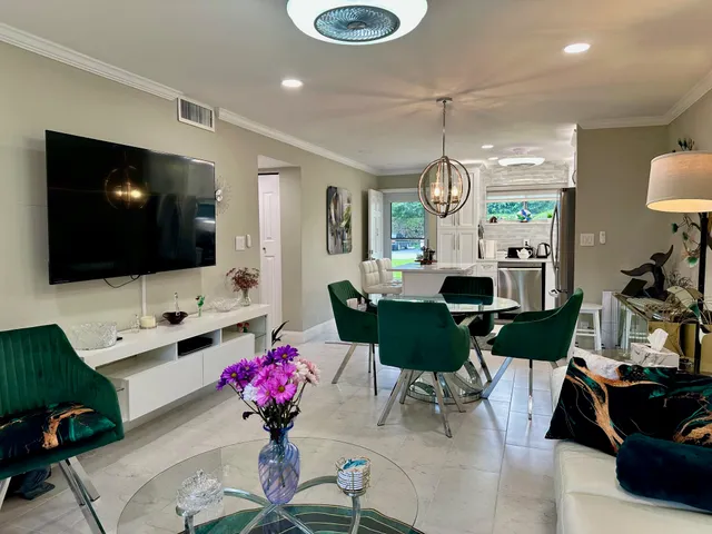 a living room with furniture a flat screen tv and kitchen view