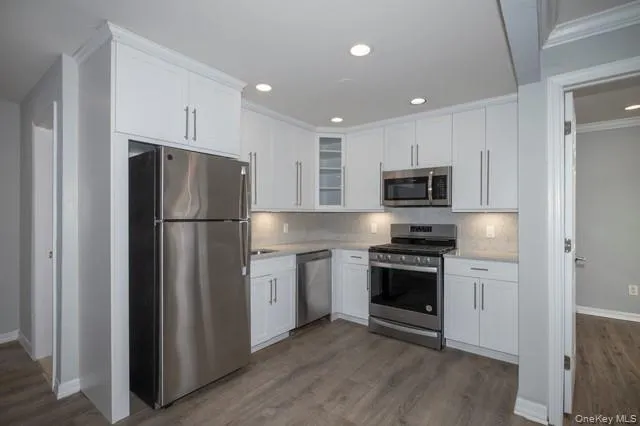 a kitchen with cabinets stainless steel appliances and wooden floor