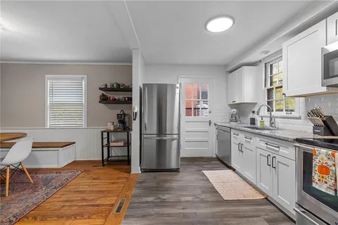 a kitchen with a refrigerator wooden floor a dining table and chairs