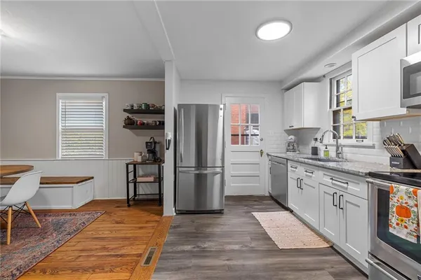a kitchen with a refrigerator wooden floor a dining table and chairs