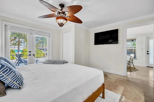 a bedroom with a bed a flat screen tv and a window