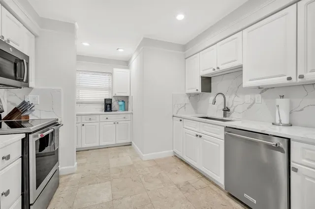 a kitchen with granite countertop white cabinets and stainless steel appliances
