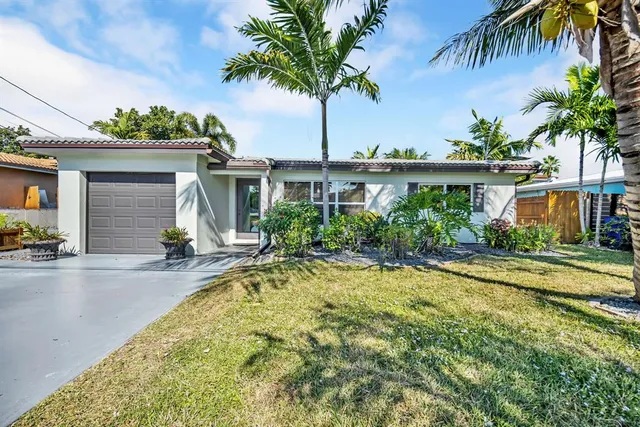 front view of house with a yard and palm trees