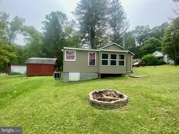 a view of a wooden house with a yard and large trees