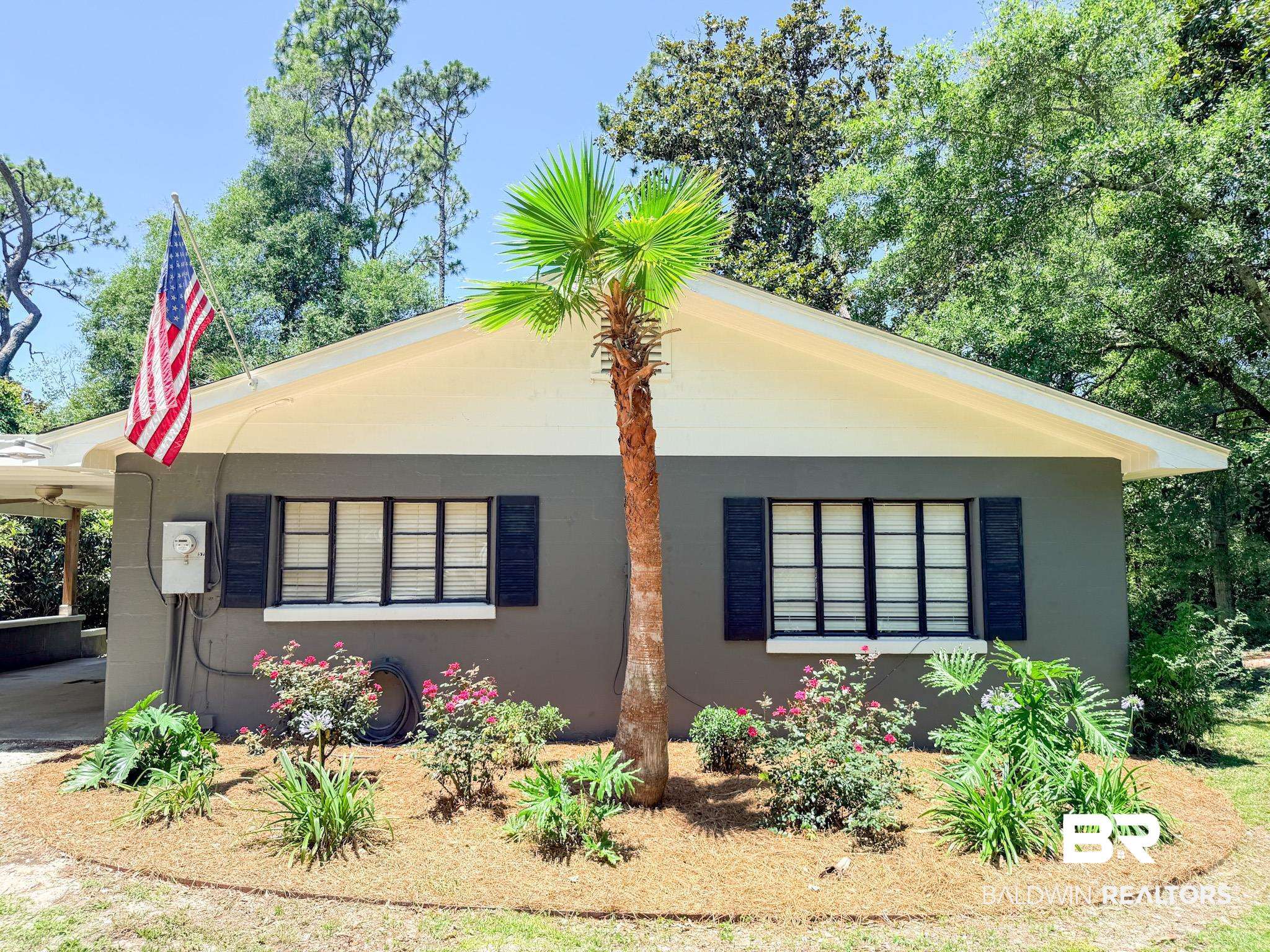 18711 Keller Road Foley, AL 36535 - Photo 2 of 38 Front exterior featuring a palm tree, a gable roofline, black louvered shutters, a carport, and established landscaping with pine straw ground cover