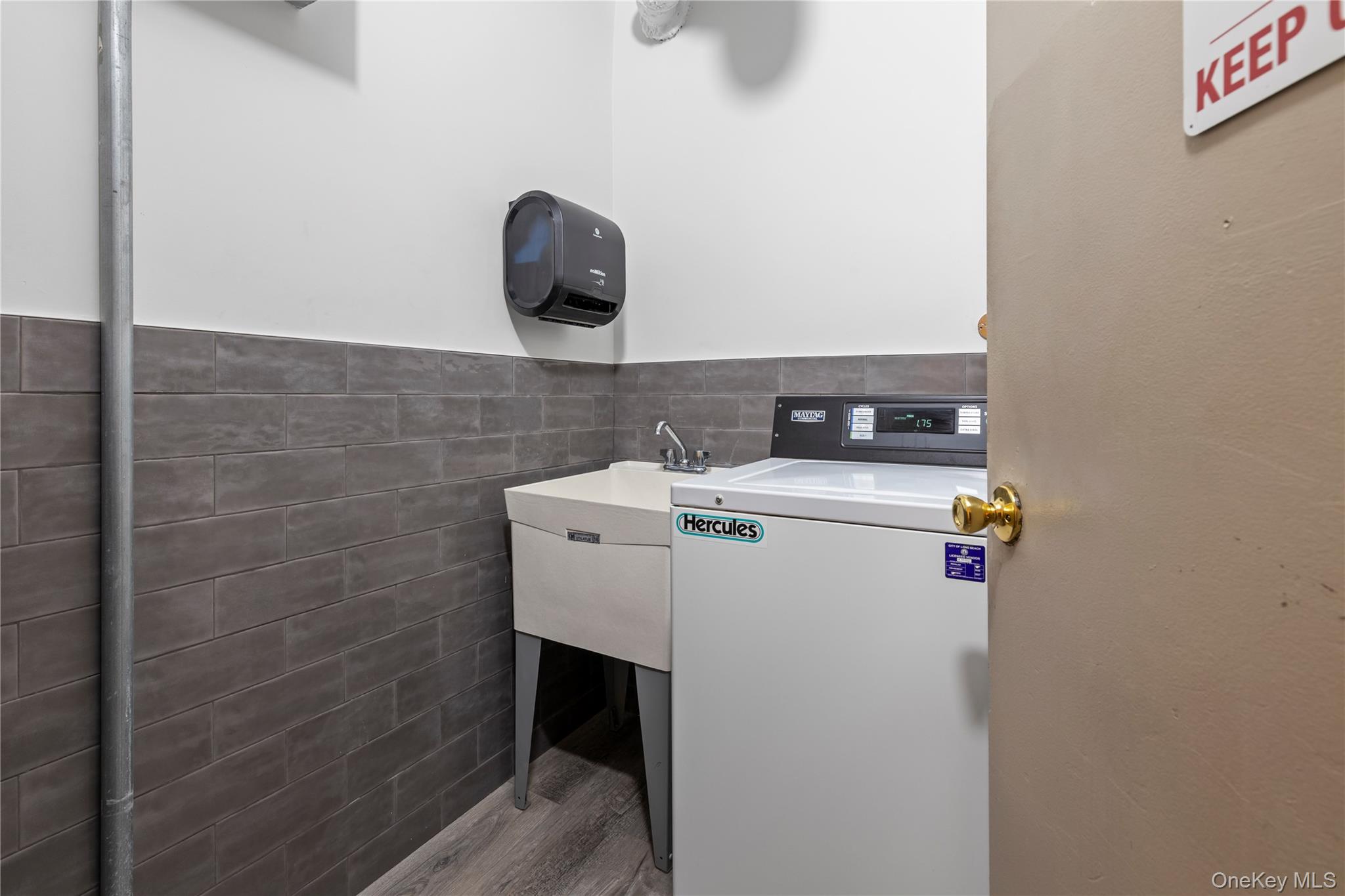 711 Shore Road, Unit 3B Long Beach, NY 11561 - Photo 13 of 20 Laundry room with washer / clothes dryer, tile walls, wood finished floors, and a wainscoted wall