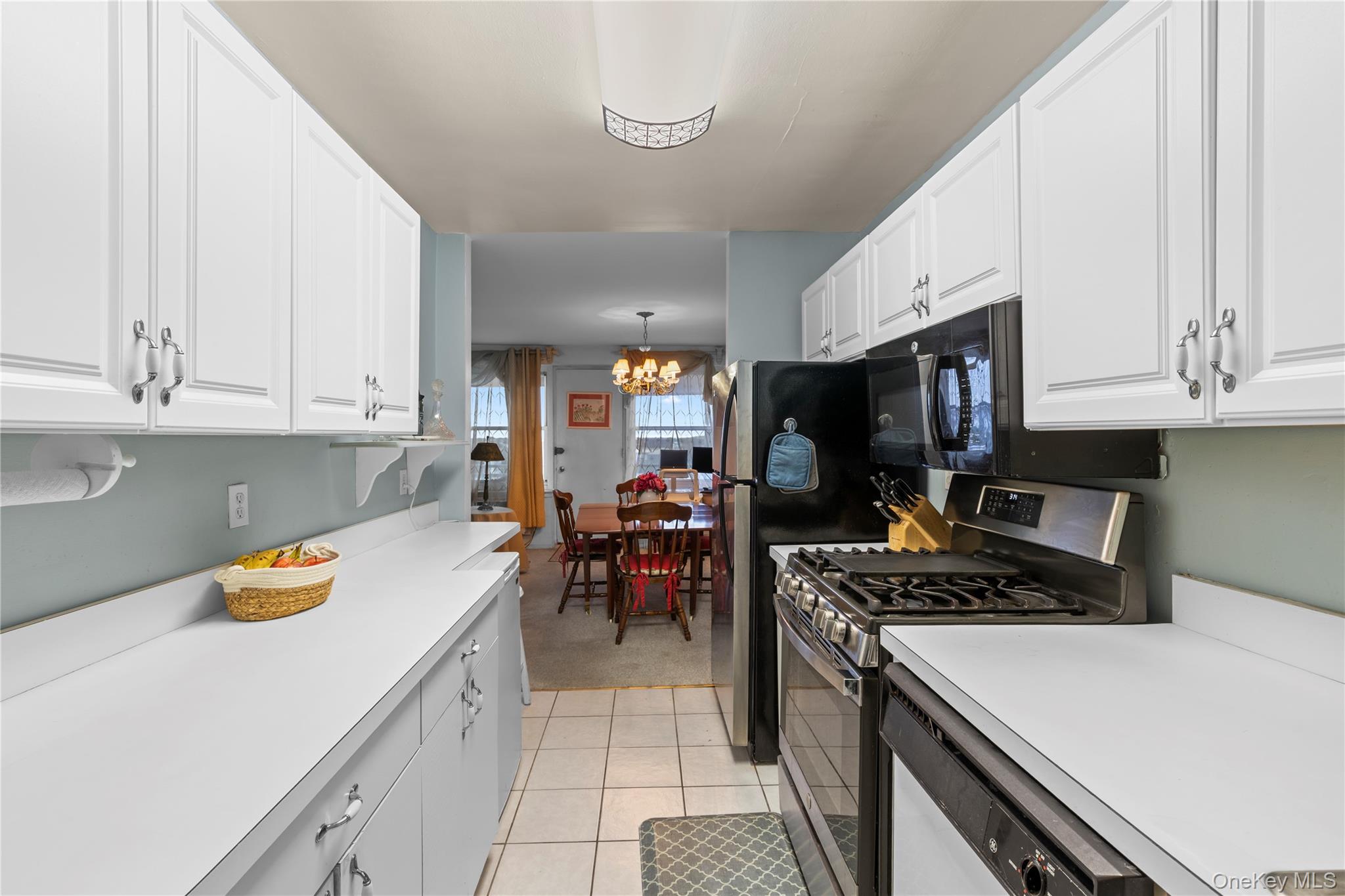 711 Shore Road, Unit 3B Long Beach, NY 11561 - Photo 6 of 20 Kitchen with gas stove, white cabinetry, light countertops, light tile patterned flooring, and dishwashing machine