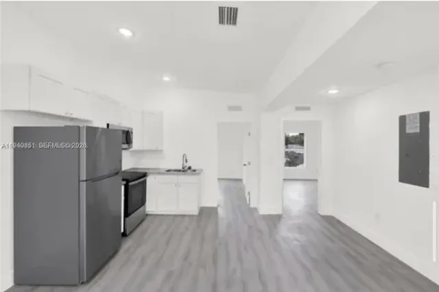 a view of a kitchen with a refrigerator and wooden floor