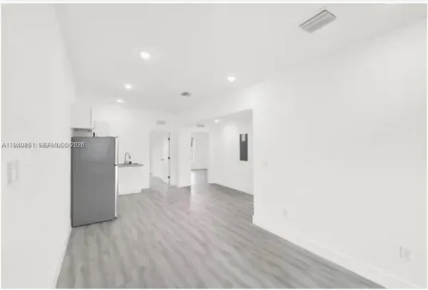 a view of a hallway with wooden floor and a bathroom