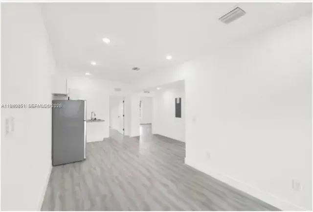 a view of a hallway with wooden floor and a bathroom