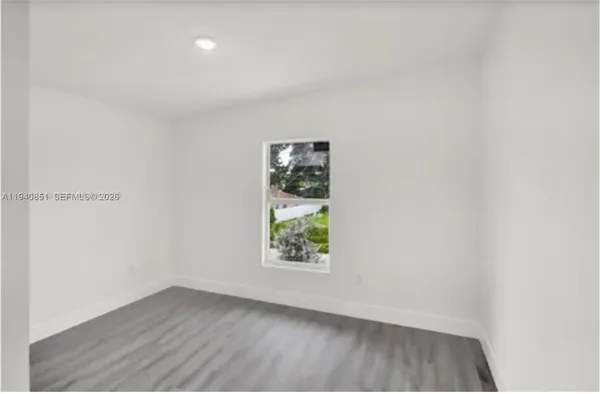 a view of an empty room with wooden floor and windows