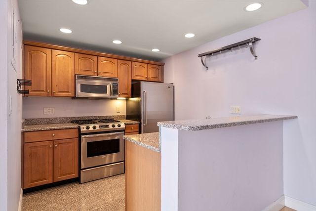 a kitchen with stainless steel appliances granite countertop a refrigerator a stove top oven a sink and dishwasher