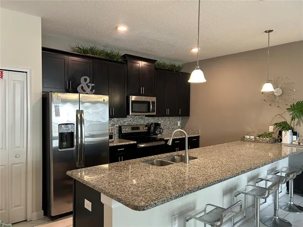 a kitchen with stainless steel appliances granite countertop a sink a stove and a refrigerator
