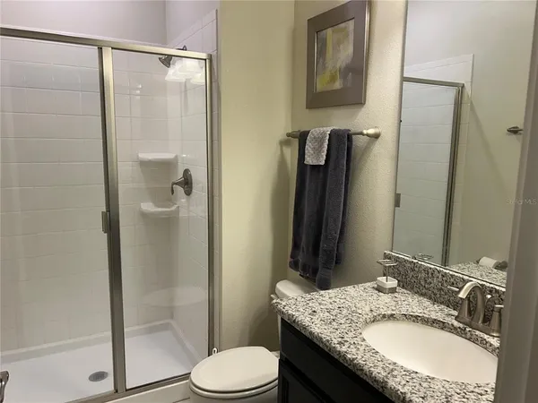 a bathroom with a granite countertop sink toilet and shower