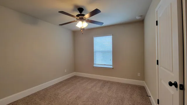 an empty room with a window and a fan