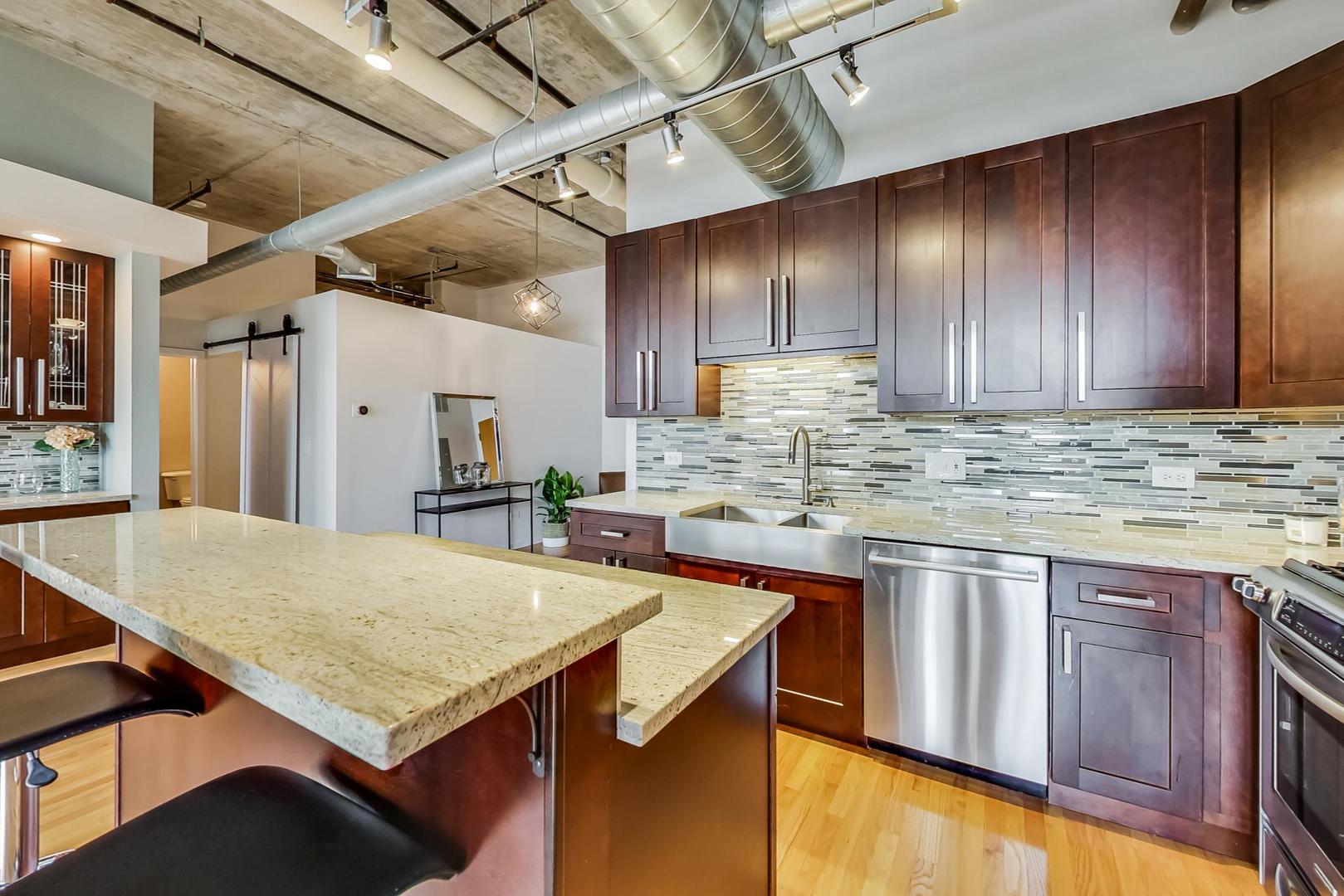 933 West Van Buren Street, Unit 903 Chicago, IL 60607 - Photo 20 of 50 a kitchen with stainless steel appliances granite countertop wooden cabinets a sink and dishwasher