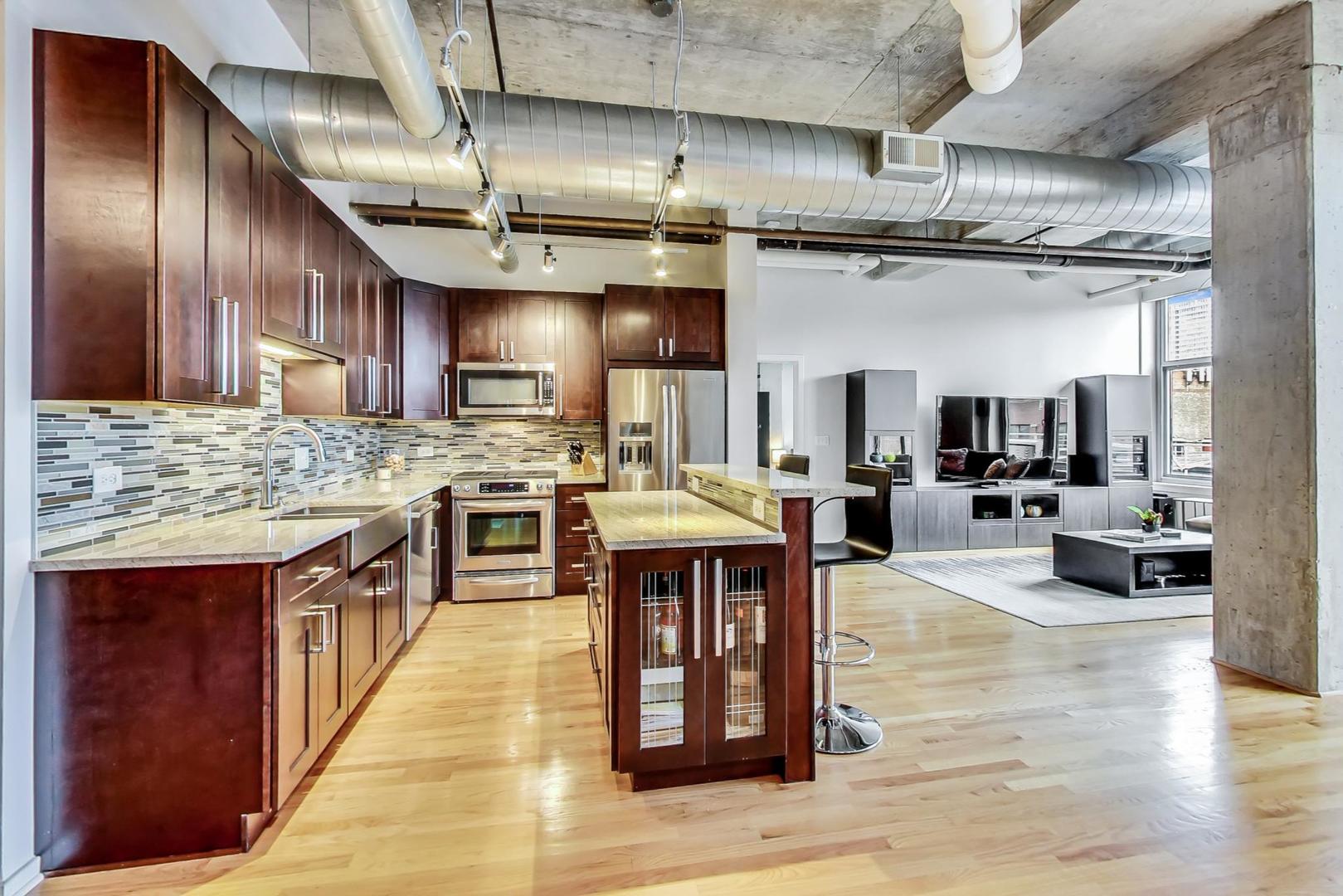 933 West Van Buren Street, Unit 903 Chicago, IL 60607 - Photo 21 of 50 a open kitchen with stainless steel appliances granite countertop a large stove a sink dishwasher and cabinets with wooden floor