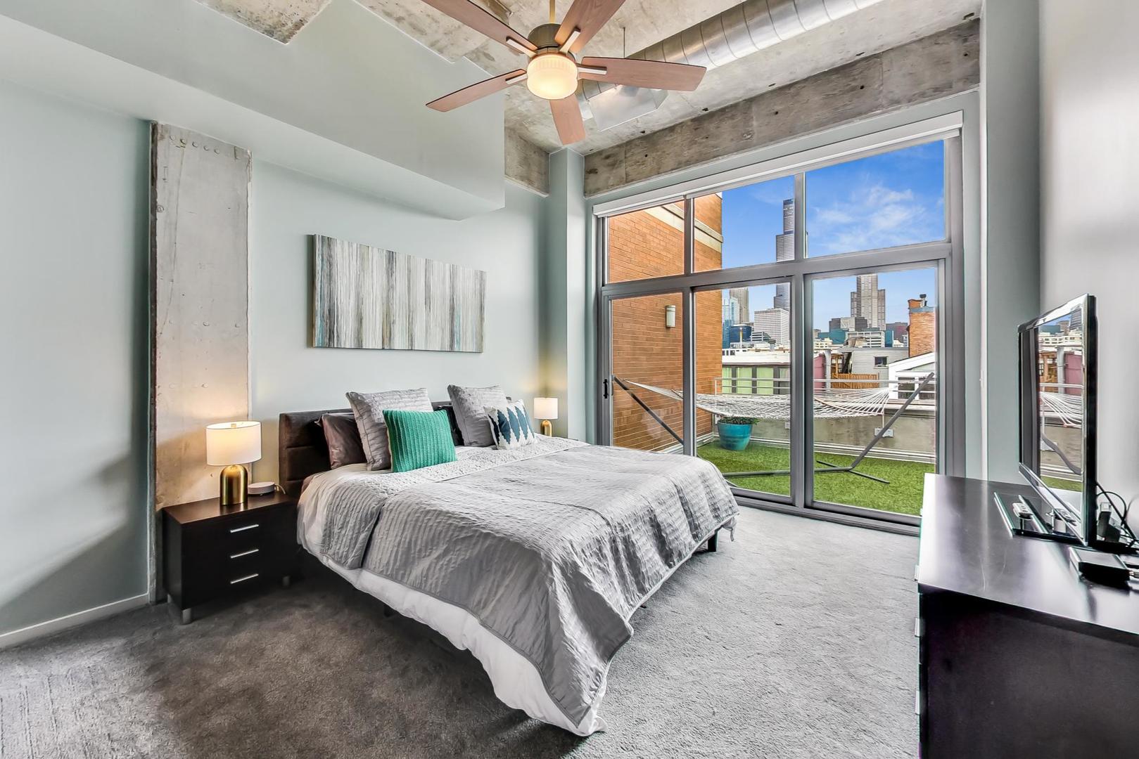 933 West Van Buren Street, Unit 903 Chicago, IL 60607 - Photo 22 of 50 a bedroom with a bed flat screen tv and a large window