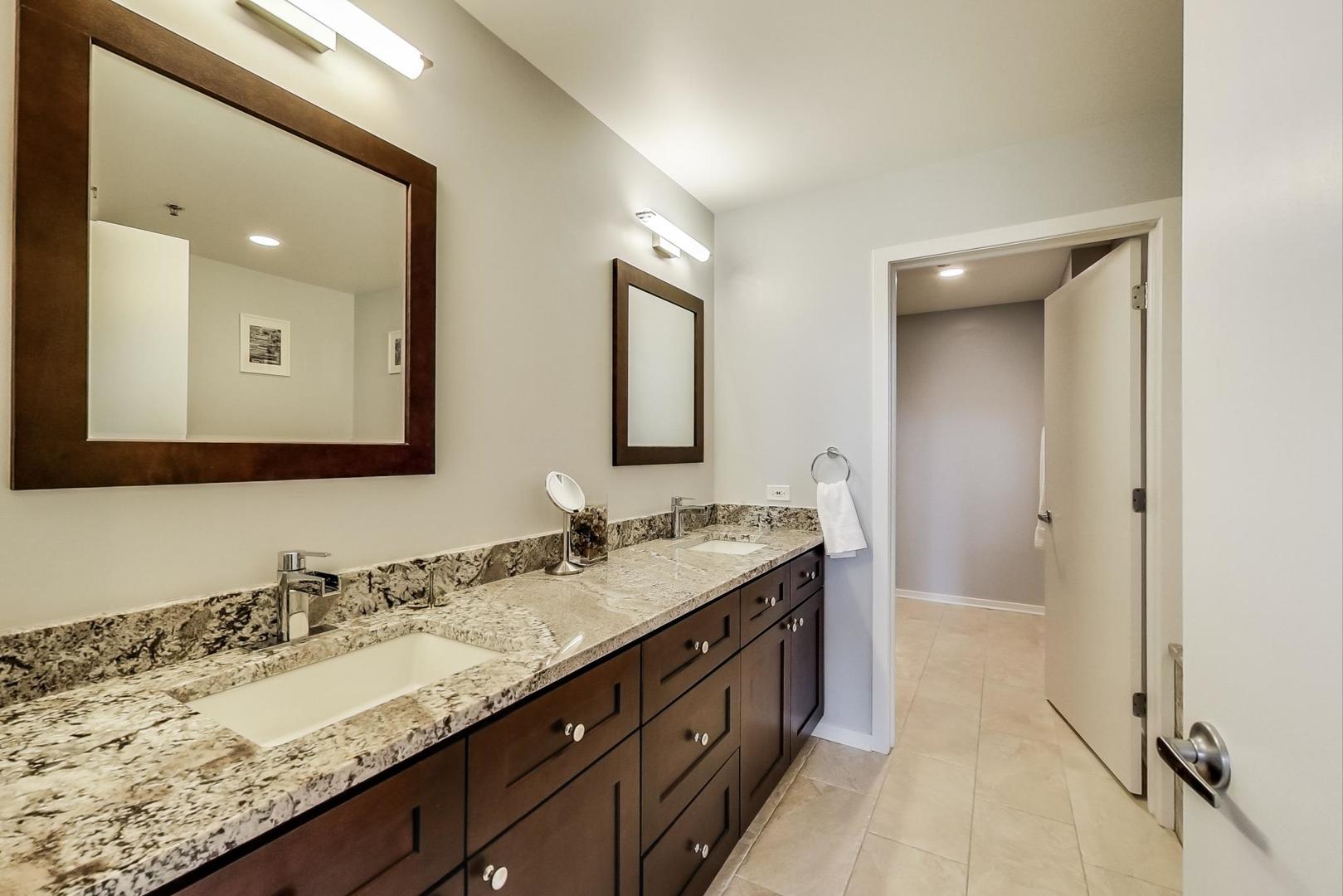 933 West Van Buren Street, Unit 903 Chicago, IL 60607 - Photo 26 of 50 a bathroom with a granite countertop double vanity sink and a mirror