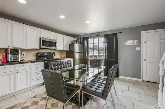 a kitchen with stainless steel appliances kitchen island granite countertop a refrigerator a stove a sink a dining table and chairs with wooden floor