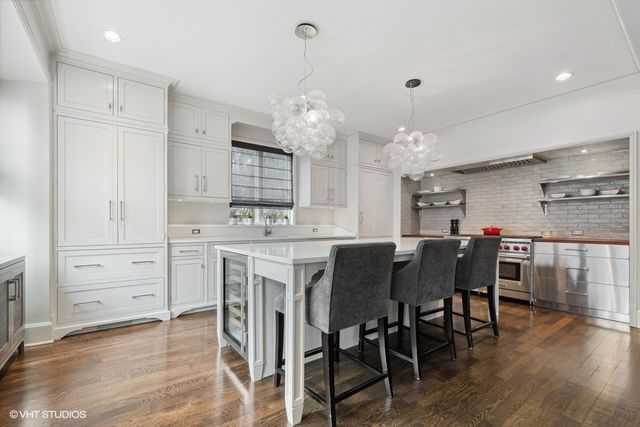 a kitchen with a stove a refrigerator and a dining table with wooden floor