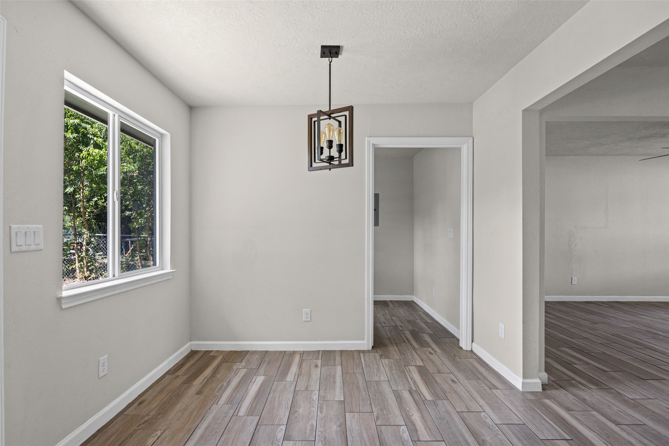 Gleaming plank floors and an open doorway connect this dining space to neighboring rooms.