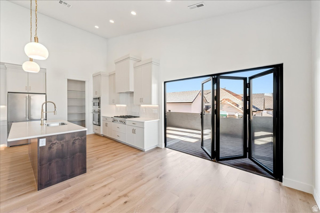 1491 East Centaurus Way, Unit 86 Washington, UT 84780 - Photo 7 of 26 Kitchen featuring a high ceiling, hanging light fixtures, white cabinetry, an island with sink, and stainless steel appliances
