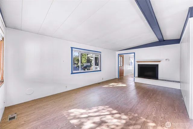 an empty room with windows and fireplace