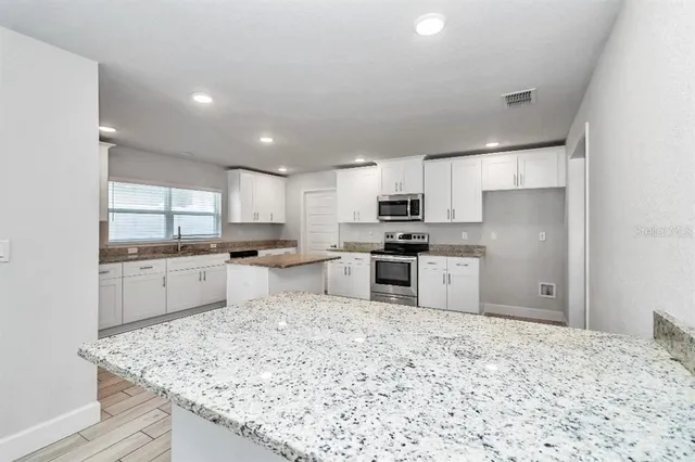 a kitchen with stainless steel appliances kitchen island granite countertop a refrigerator sink and cabinets