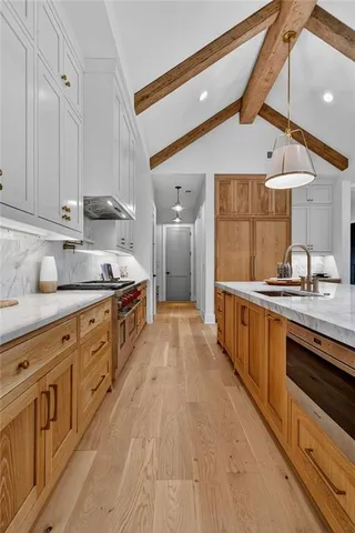 a kitchen with stainless steel appliances granite countertop a refrigerator a sink dishwasher a stove and white cabinets with wooden floor