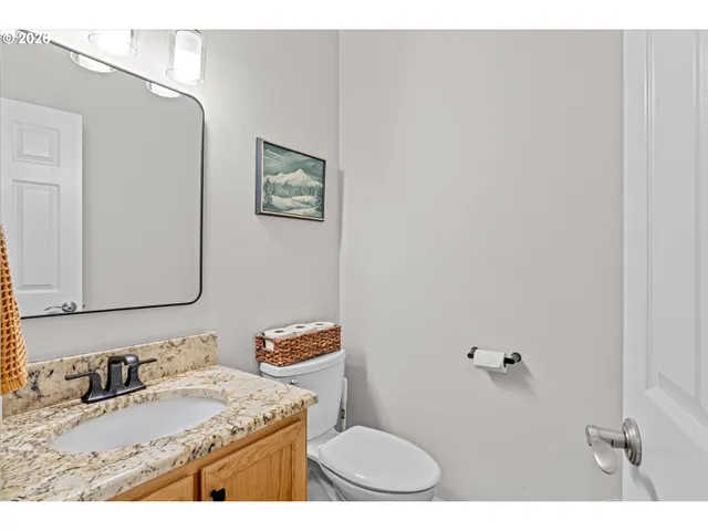 a bathroom with a granite countertop sink mirror vanity and toilet