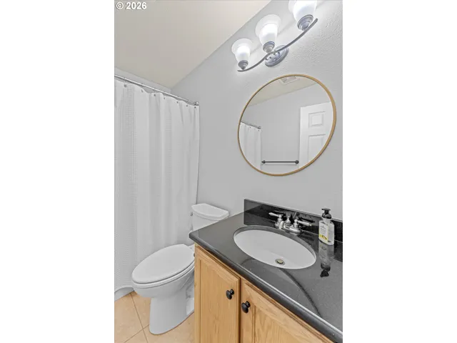 a bathroom with a granite countertop sink a toilet and a mirror