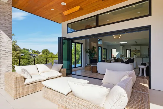 a view of a kitchen with kitchen island a large window cabinets a sink and stainless steel appliances