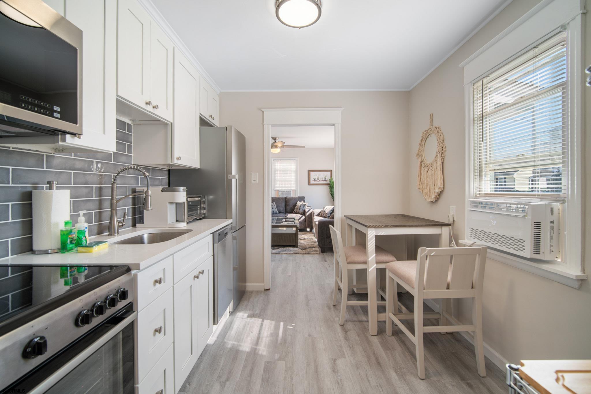 207 13th Street North Brigantine, NJ 08203 - Photo 27 of 44 a kitchen with stainless steel appliances a stove top oven a sink dishwasher and a dining table with wooden floor