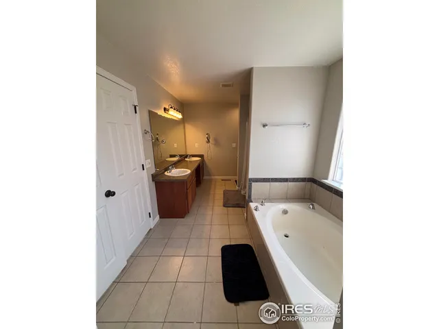 a bathroom with a tub shower sink and mirror