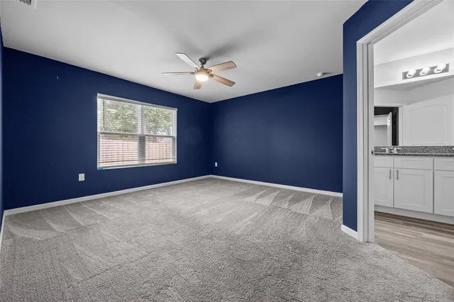 an empty room with windows and fan